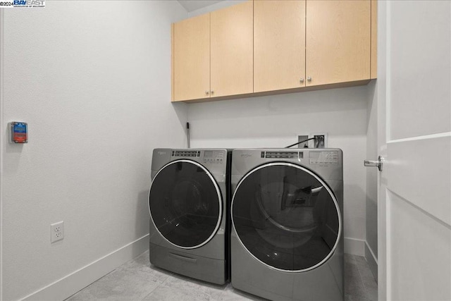 laundry room featuring light tile patterned flooring, separate washer and dryer, and cabinets