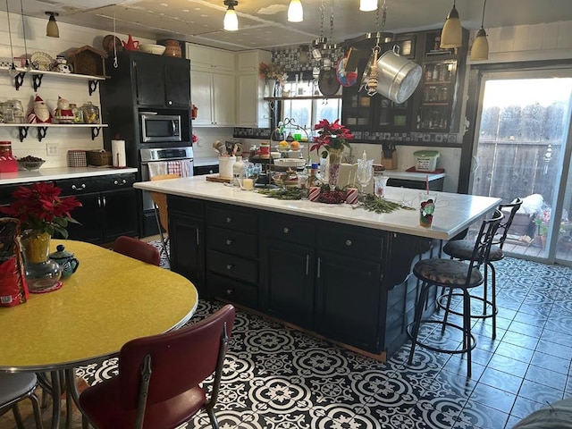 kitchen with tile patterned flooring, decorative light fixtures, a center island, and appliances with stainless steel finishes