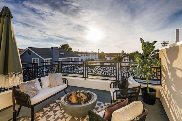 view of patio / terrace with a balcony and an outdoor living space with a fire pit