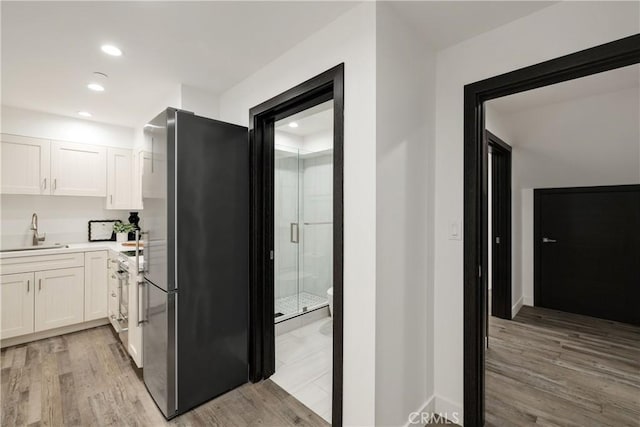 kitchen featuring white cabinetry, sink, light wood-type flooring, and appliances with stainless steel finishes