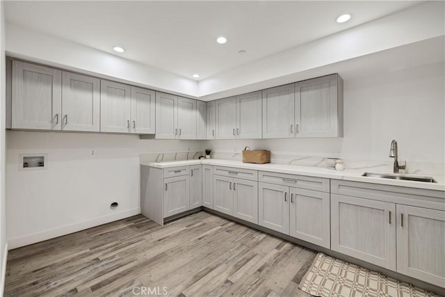 laundry room featuring washer hookup, sink, cabinets, and light hardwood / wood-style floors