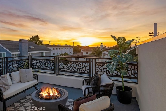 patio terrace at dusk with a balcony and an outdoor living space with a fire pit