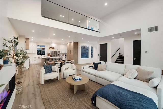 living room featuring a towering ceiling and light hardwood / wood-style floors