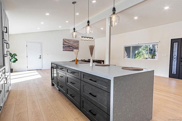 kitchen featuring decorative light fixtures, light hardwood / wood-style floors, a large island, and vaulted ceiling with beams