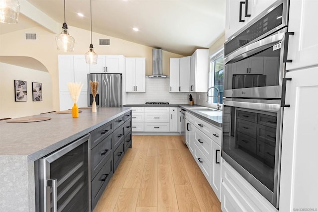 kitchen with white cabinets, appliances with stainless steel finishes, wine cooler, and wall chimney range hood