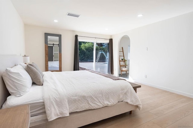 bedroom with a barn door and light hardwood / wood-style flooring