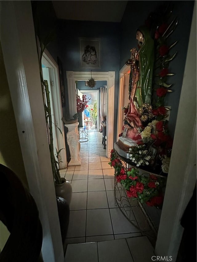 hall with light tile patterned floors and a notable chandelier