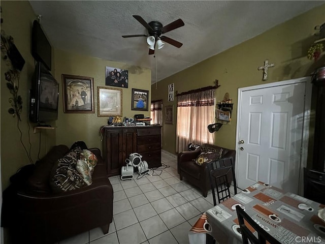 living room featuring ceiling fan, light tile patterned floors, and a textured ceiling