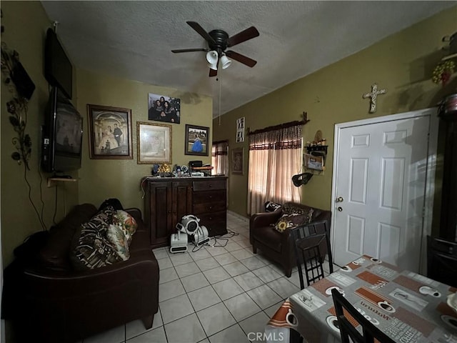 living room featuring light tile patterned flooring, ceiling fan, and a textured ceiling