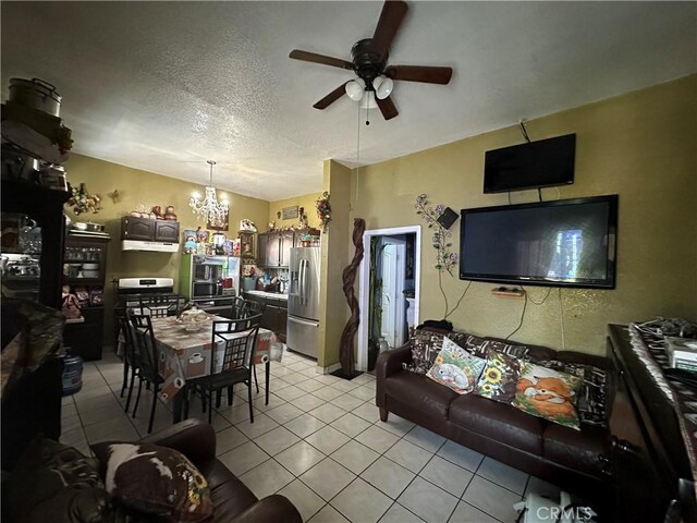 living room with ceiling fan with notable chandelier, light tile patterned floors, and a textured ceiling