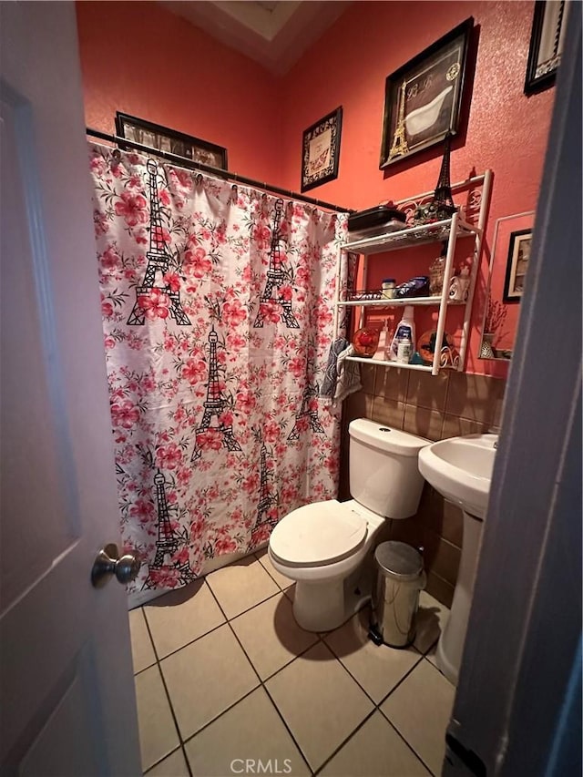 bathroom with toilet, tile patterned flooring, and tile walls