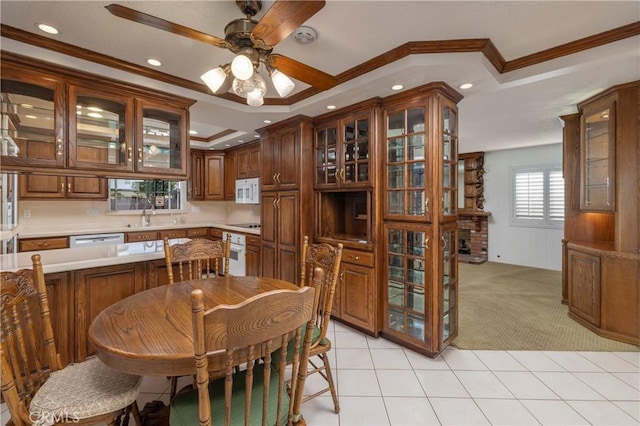 carpeted dining space featuring a raised ceiling, ceiling fan, crown molding, and sink