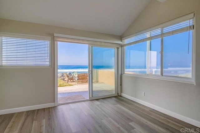 empty room featuring plenty of natural light, a water view, and hardwood / wood-style flooring