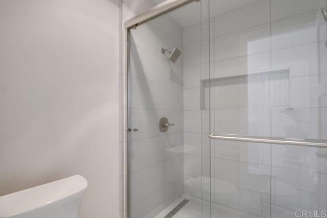 bathroom with a shower with shower door and toilet