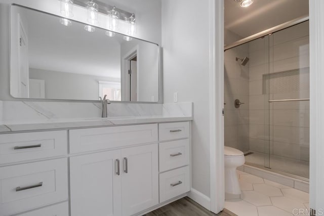 bathroom with toilet, tile patterned flooring, vanity, and walk in shower