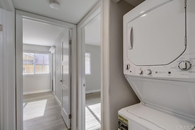 laundry area featuring light hardwood / wood-style floors and stacked washer and clothes dryer