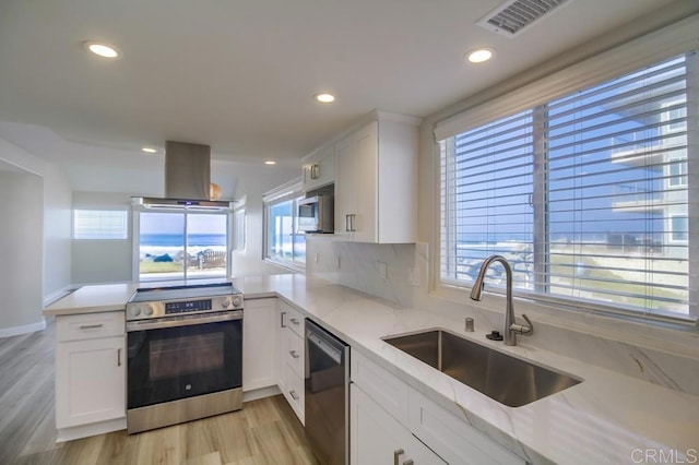 kitchen featuring sink, a wealth of natural light, island range hood, white cabinetry, and stainless steel appliances