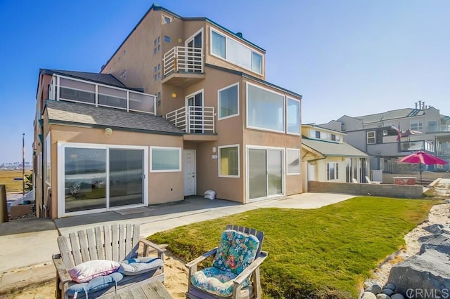 rear view of house with a yard, a balcony, and a patio