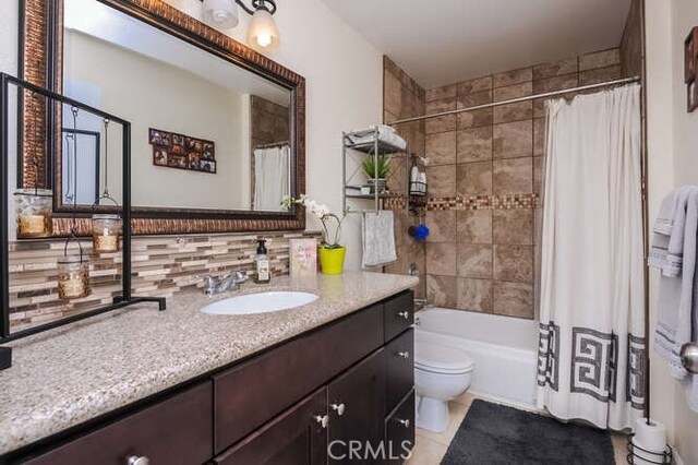 full bathroom featuring vanity, shower / bath combo, backsplash, and toilet