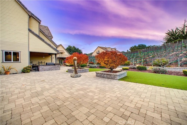 patio terrace at dusk with a lawn and exterior kitchen