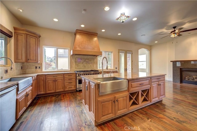 kitchen with custom exhaust hood, stainless steel range, sink, dishwasher, and dark hardwood / wood-style floors