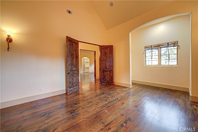 spare room with high vaulted ceiling and dark wood-type flooring