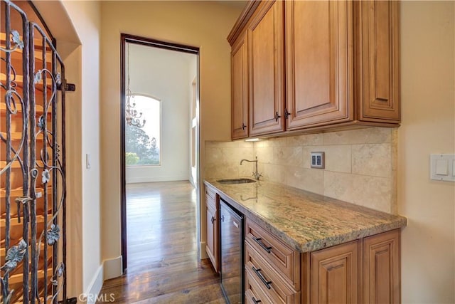 kitchen with sink, dark wood-type flooring, wine cooler, light stone counters, and decorative backsplash