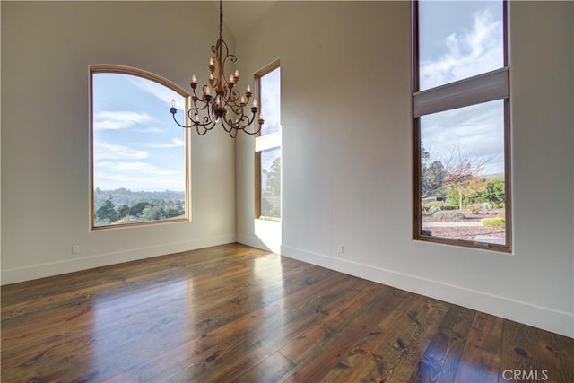 unfurnished room with dark hardwood / wood-style flooring and an inviting chandelier