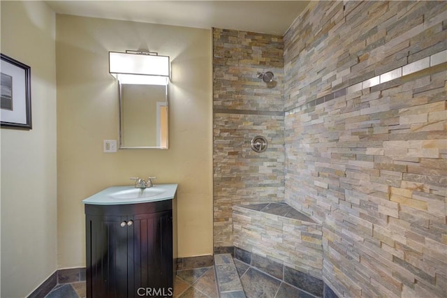 bathroom with a tile shower and vanity