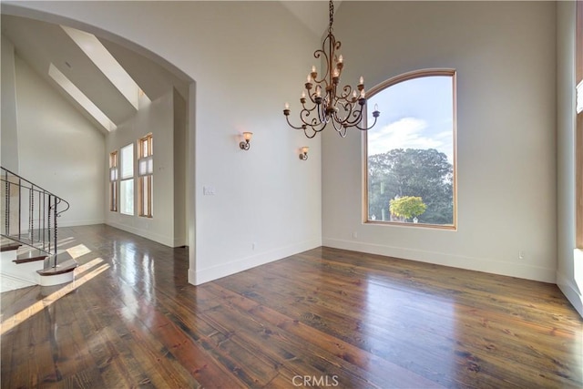 unfurnished dining area featuring high vaulted ceiling, a chandelier, and dark hardwood / wood-style floors