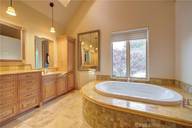 bathroom featuring vanity, high vaulted ceiling, and tiled tub