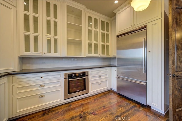 kitchen with decorative backsplash, dark hardwood / wood-style flooring, white cabinetry, and stainless steel appliances