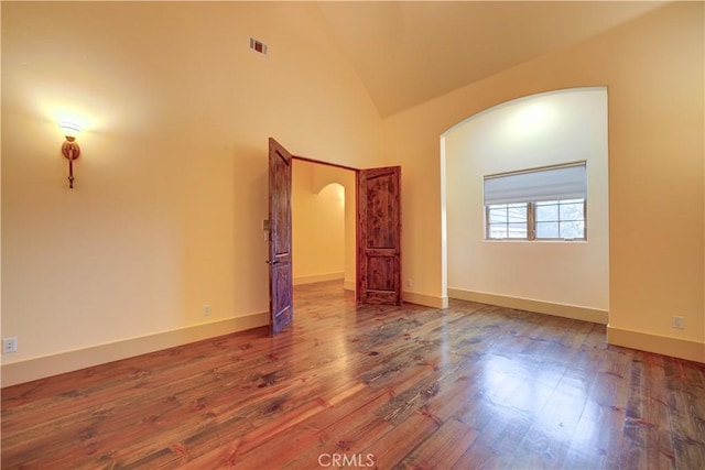 unfurnished room with wood-type flooring and high vaulted ceiling