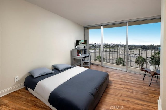 bedroom featuring access to outside, expansive windows, and wood-type flooring