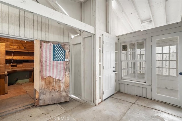 miscellaneous room with vaulted ceiling and wood walls