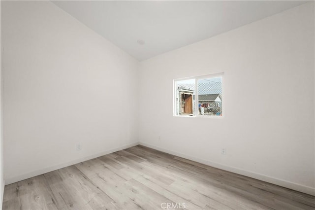 unfurnished room with vaulted ceiling and light wood-type flooring