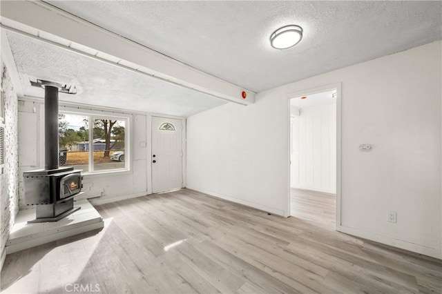 interior space featuring a textured ceiling, light wood-type flooring, and a wood stove