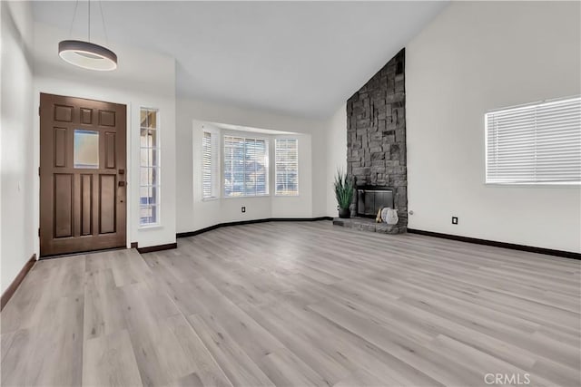 foyer entrance with high vaulted ceiling, a fireplace, and light hardwood / wood-style floors