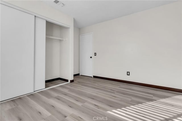 unfurnished bedroom with light hardwood / wood-style floors and a closet