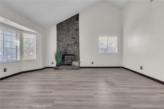 unfurnished living room featuring high vaulted ceiling, light wood-type flooring, and a fireplace