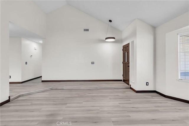 empty room featuring high vaulted ceiling and light wood-type flooring