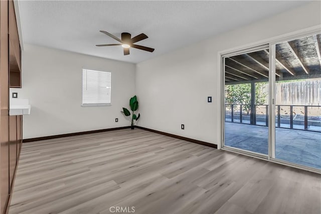 empty room with plenty of natural light, ceiling fan, and light hardwood / wood-style flooring