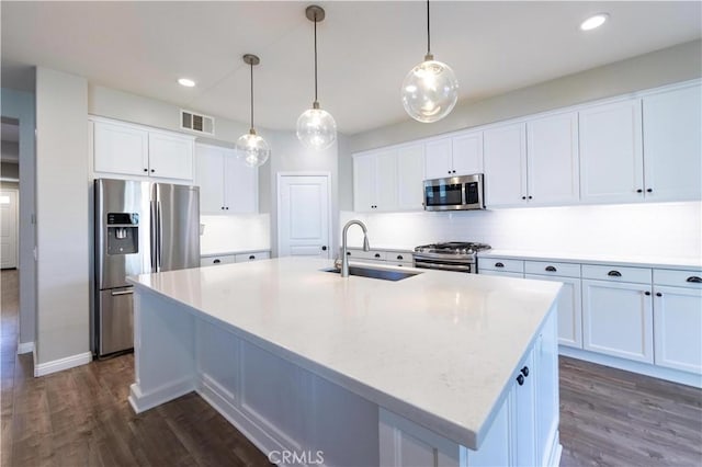 kitchen featuring appliances with stainless steel finishes, a kitchen island with sink, sink, and white cabinets