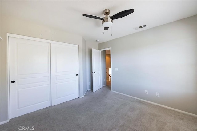 unfurnished bedroom featuring ceiling fan, light colored carpet, and a closet