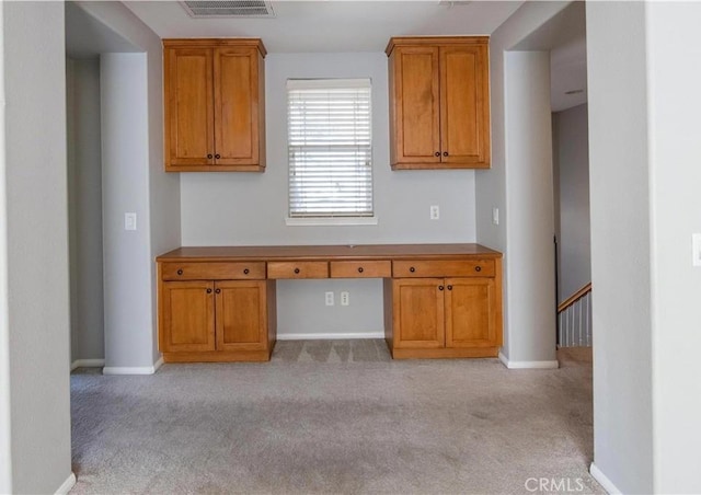 kitchen featuring built in desk and light colored carpet