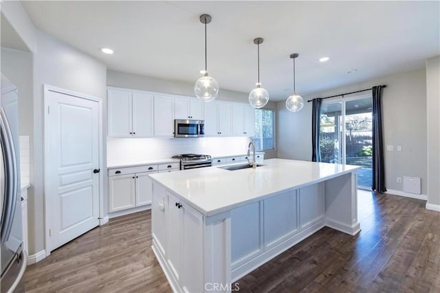 kitchen with stainless steel appliances, a kitchen island with sink, sink, and white cabinets