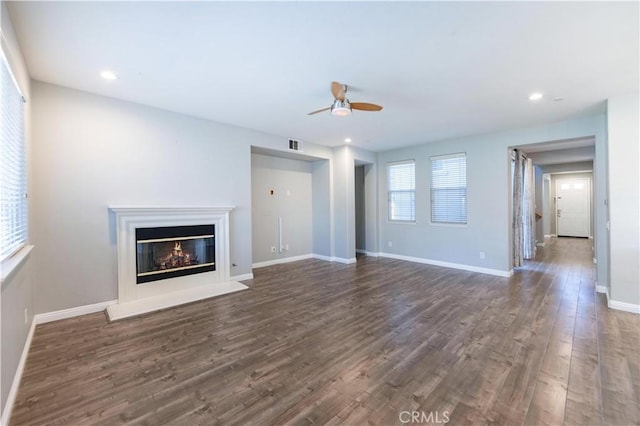 unfurnished living room featuring dark wood-type flooring and ceiling fan