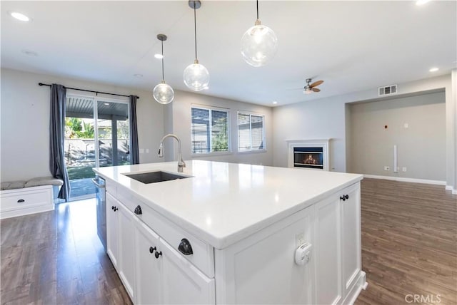 kitchen featuring sink, white cabinetry, a wealth of natural light, a center island with sink, and decorative light fixtures