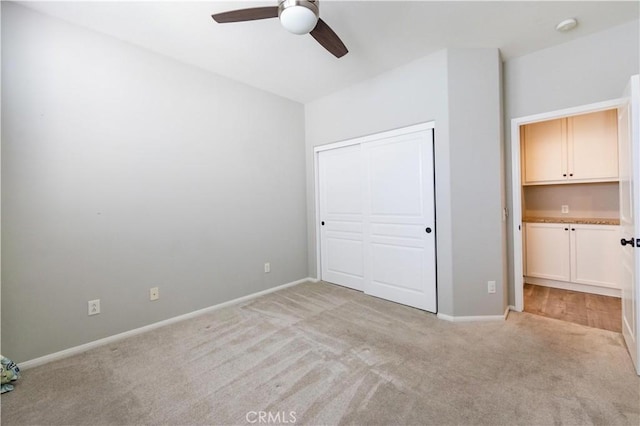 unfurnished bedroom featuring light carpet, ceiling fan, and a closet