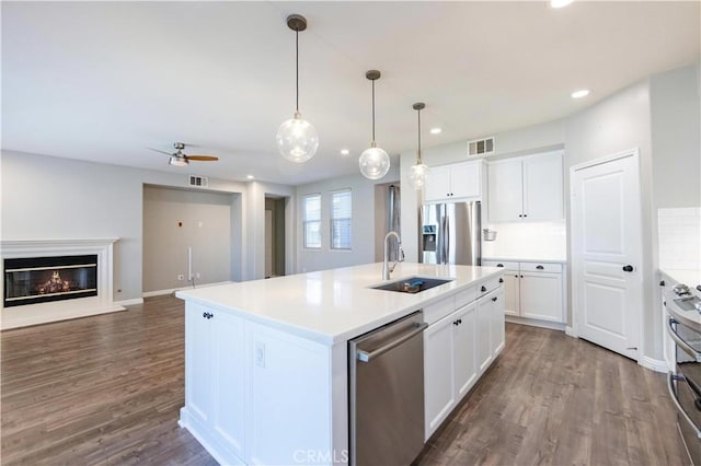 kitchen featuring sink, white cabinetry, a center island with sink, dark hardwood / wood-style floors, and stainless steel appliances